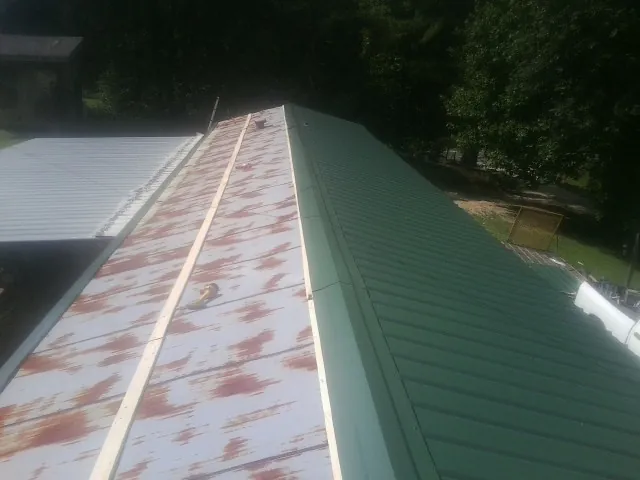 Old rusted panels beside newly installed green metal roofing in Point Pleasant Beach