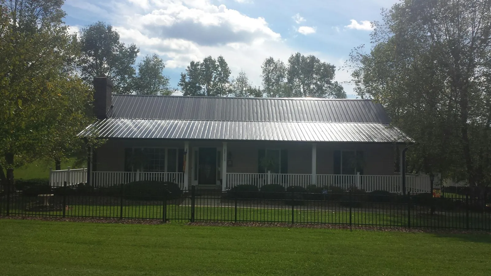 Gray metal roof on a brick ranch with a full width front porch — Gutter Guard Installation work by our crew in Point Pleasant Beach