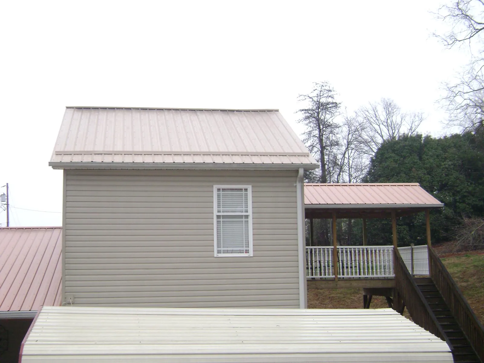 Tan metal roofs on a two story addition and attached porch, from a Roof Replacement job in Point Pleasant Beach