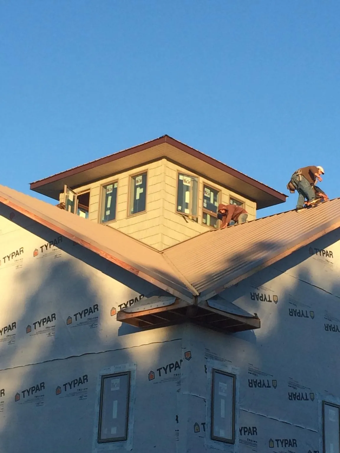 Roofers working around a rooftop cupola on a new metal roof at sunset — Roof Waterproofing in Point Pleasant Beach by Roofing Brothers